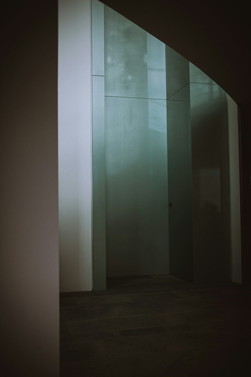 Modernes Büro-Interieur mit Milchglaswänden und dunklen Fliesen.