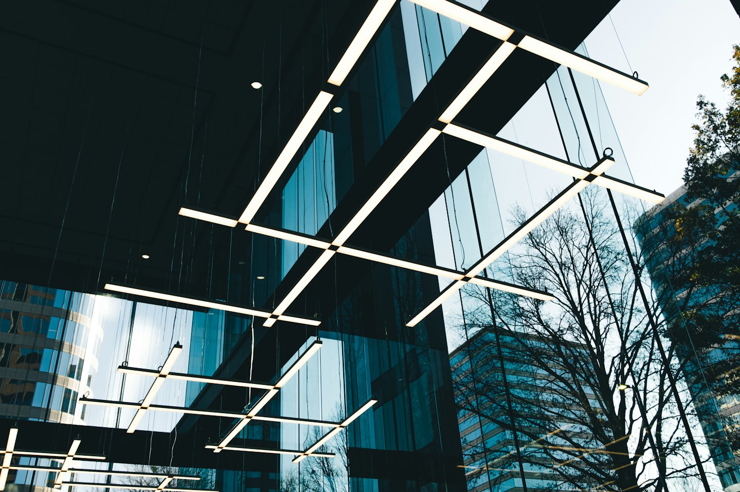 Lineare LED-Leuchten bilden ein Raster an der dunklen Decke.